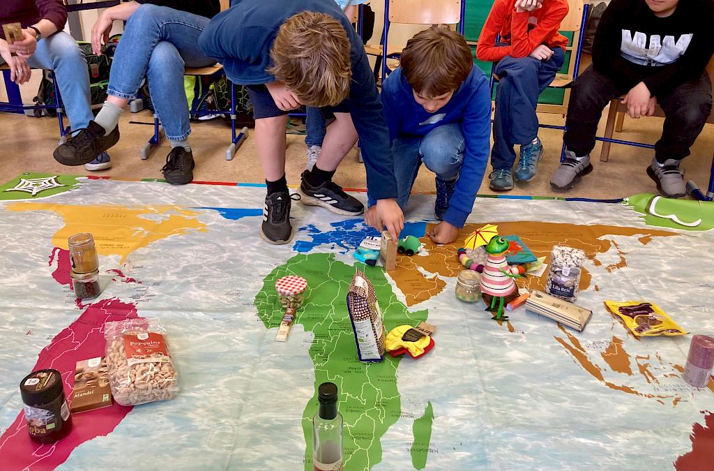 Kinder ordnen fair gehandelte Produkte auf einer großen Weltkarte zu.