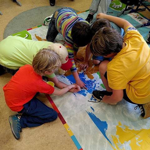 Auf der großen Weltkarte entdecken Kinder Wege des Fairen Handels.